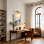 Redmond Brass Picture Wall Lamp | Brass and Metal | Illuminating a colorful wall painting above a wooden study desk | Severn Lighting