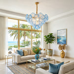 Rosalind Petal Glass Chandelier | Textured Spiral Blue Glass and Gold Metal | Hanging from the ceiling in a bright oceanfront lounge with a white couch and gold decor | Severn Lighting
