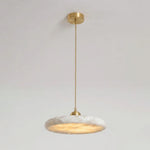 Sabine Alabaster Disc Pendant Light | Natural Alabaster and Brass | Medium close-up glowing softly against a bright window backdrop | Severn Lighting