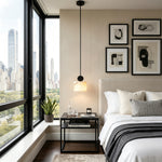 Sabine Alabaster Drum Pendant Light | Natural Alabaster and Brass | Hanging over a black nightstand in a modern bedroom with a large city view window | Severn Lighting