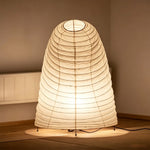 Severine Spiral Washi Paper Table Lamp | Washi Paper and Metal | Front illuminated view glowing softly on the floor in a dark setting | Severn Lighting