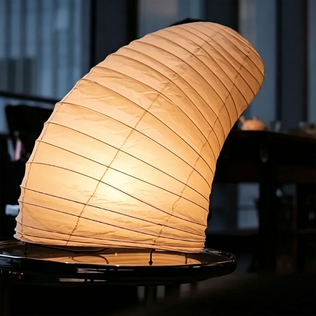 Severine Spiral Washi Paper Table Lamp | Washi Paper and Metal | Side profile view of the glowing curved paper shade in a dark room | Severn Lighting