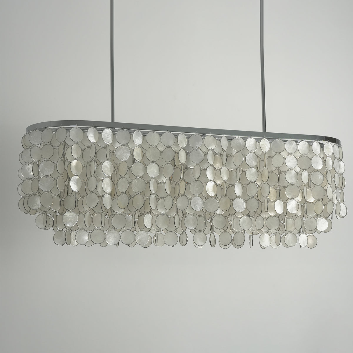 Sirena Capiz Elongated Linear Chandelier | Capiz Shell, Metal | Frontal view of the unlit linear chandelier against a neutral studio grey background, showing its tiered structure | Samu Lamp