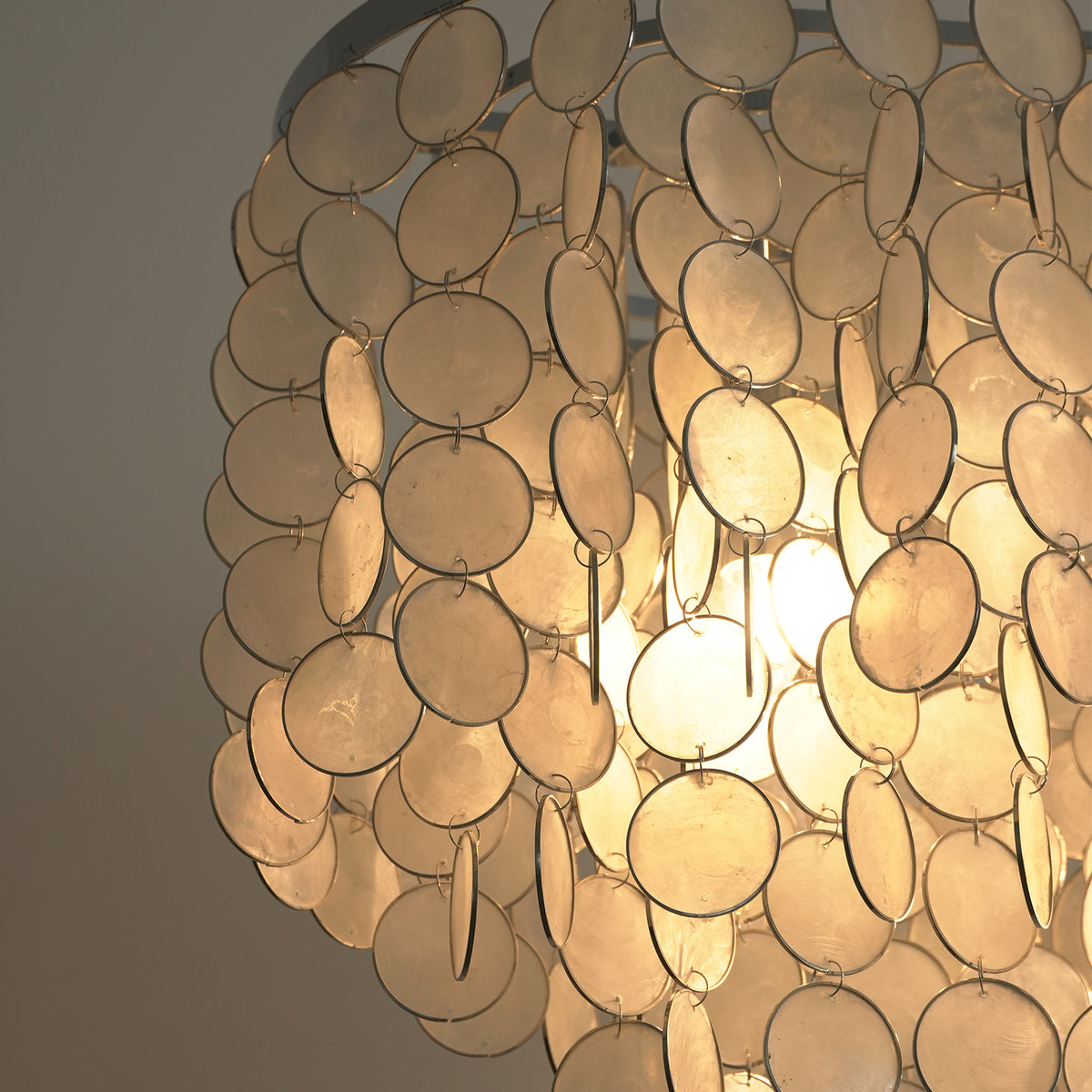 Sirena Capiz Elongated Linear Chandelier | Capiz Shell, Metal | Close-up profile of the tiered cascading shell rows shimmering with warm light | Detail shot | Samu Lamp