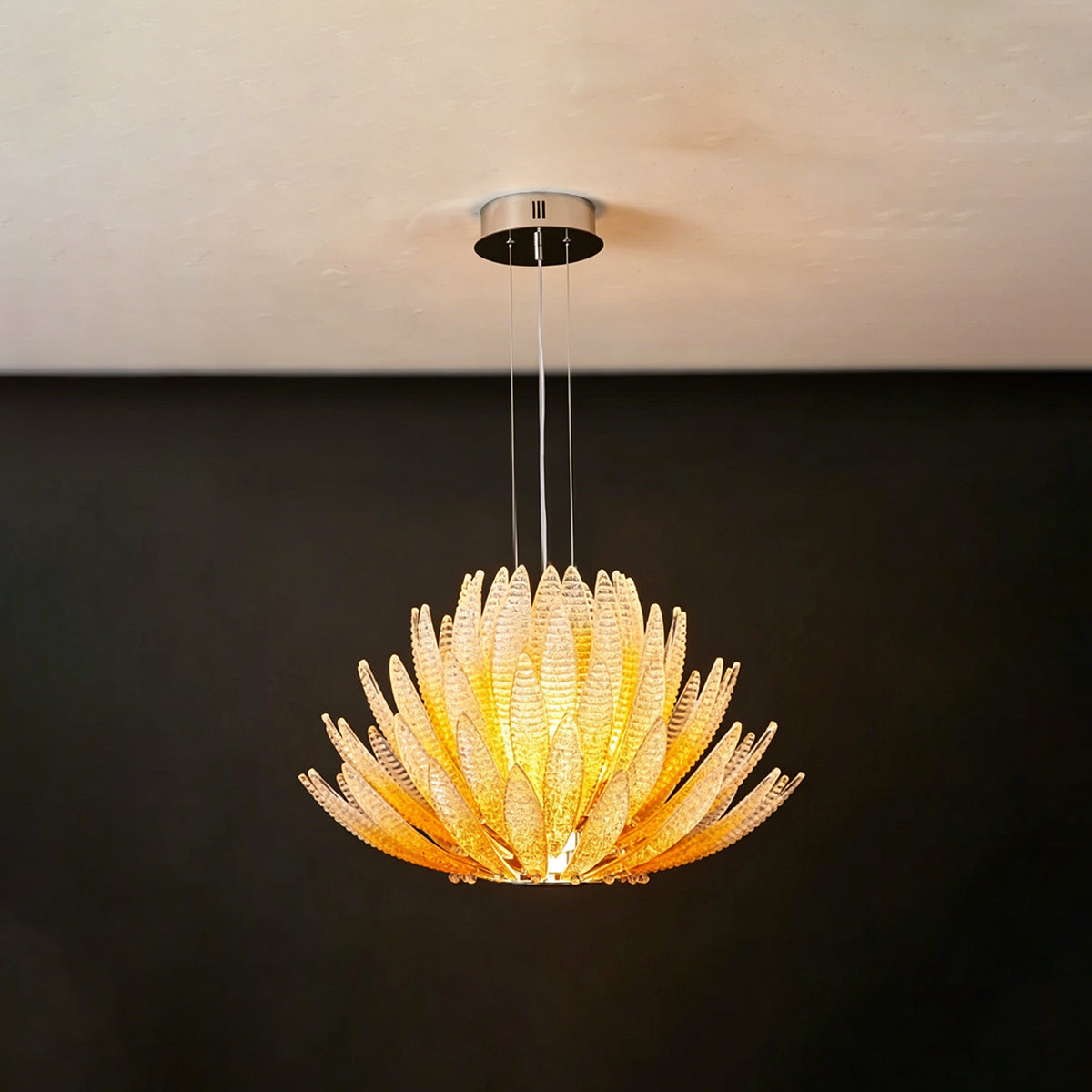 Solaris Agave Glass Starburst Chandelier | Amber Textured Glass | Minimalist frontal view of the glowing amber agave fixture on a solid dark charcoal wall | Severn Lighting