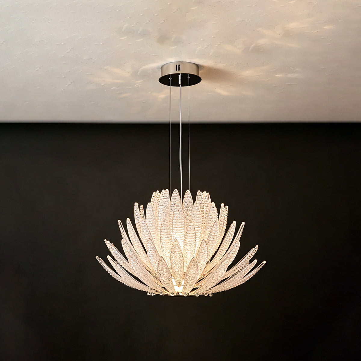 Solaris Agave Glass Starburst Chandelier | White Textured Glass | Frontal view of the glowing white glass agave fixture on a solid dark charcoal wall | Severn Lighting