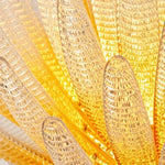 Solaris Agave Glass Starburst Chandelier | Amber Textured Glass | Macro shot focusing on the bubbly textured details of the illuminated golden glass leaves | Severn Lighting