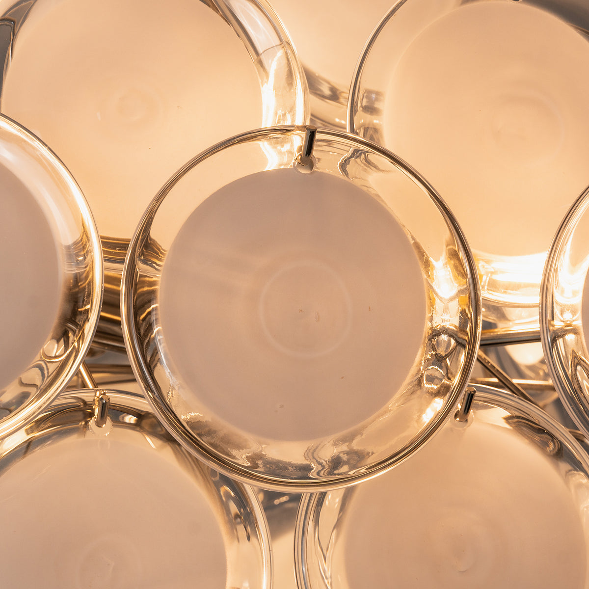 Solene Clustered Glass Disc Ceiling Light | Clear and Frosted Glass Discs | Close-up macro view highlighting the warm golden light source filtering through the round glass plates | Severn Lighting