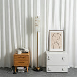 Stellan Alabaster Column Floor Lamp | Natural Alabaster, Brass and Black Metal | Styled next to a wooden nightstand in a minimalist room | Severn Lighting