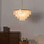 Thalassa Tiered Capiz Shell Chandelier | Capiz Shell, Metal | Staged against a plain textured wall over a dark wooden console cabinet, casting soft warm light in an elegant setting | Severn Lighting