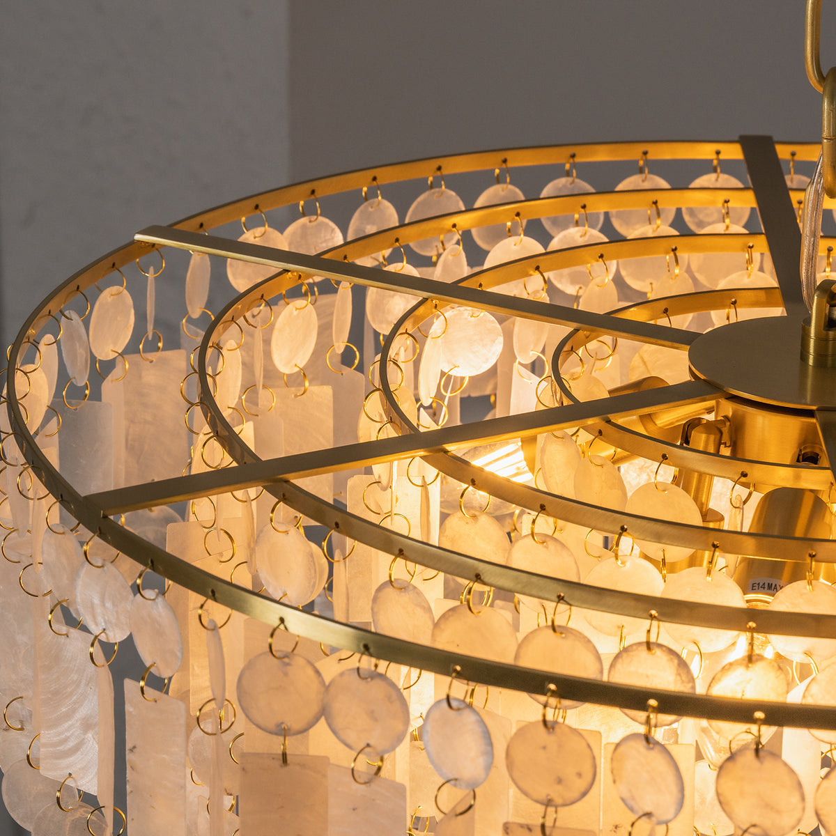 Thalassa Tiered Capiz Shell Chandelier | Capiz Shell, Metal | Top-down internal view showing the multi-tiered circular gold brass frame concentric structure and ceramic light bulb sockets | Detail shot | Severn Lighting
