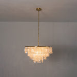 Thalassa Tiered Capiz Shell Chandelier | Capiz Shell, Metal | Full view of the illuminated tiered crystal-like shell fixture casting a soft halo against a plain grey studio backdrop | Severn Lighting