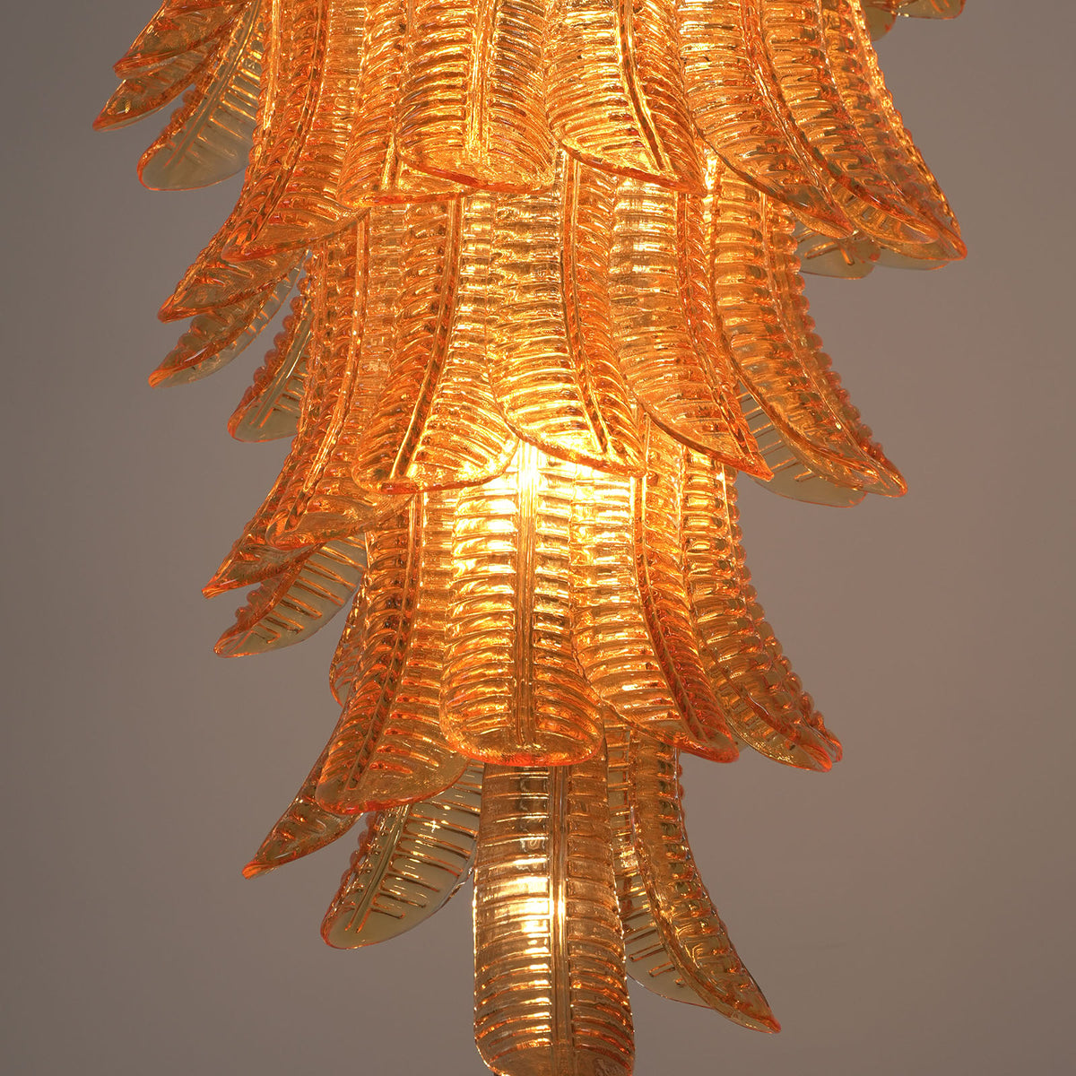 Thessaly Amber Glass Plume Chandelier | Amber Glass and Brass | Medium close-up showing the glowing bottom tiers of the chandelier | Severn Lighting