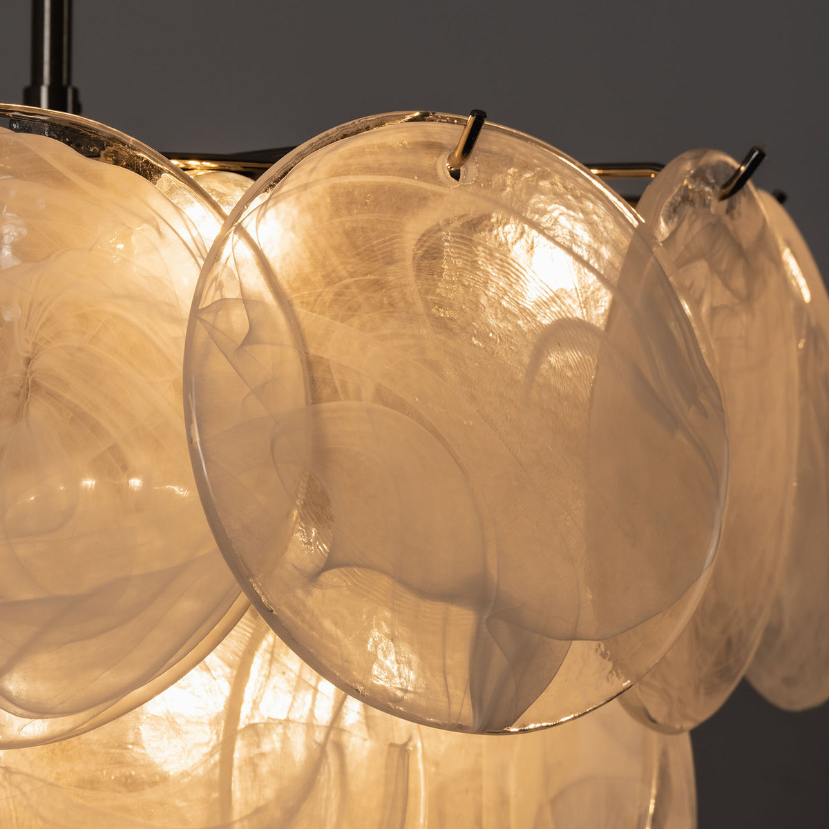 Vaucelle Swirled Glass Disc Tiered Chandelier | Swirled Glass and Brass | Close-up view of translucent glass discs attached to brass rim | Severn Lighting