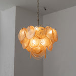 Vaucelle Swirled Glass Disc Tiered Chandelier | Swirled Glass and Brass | Yellow amber glass variant hanging illuminated in a room corner | Severn Lighting