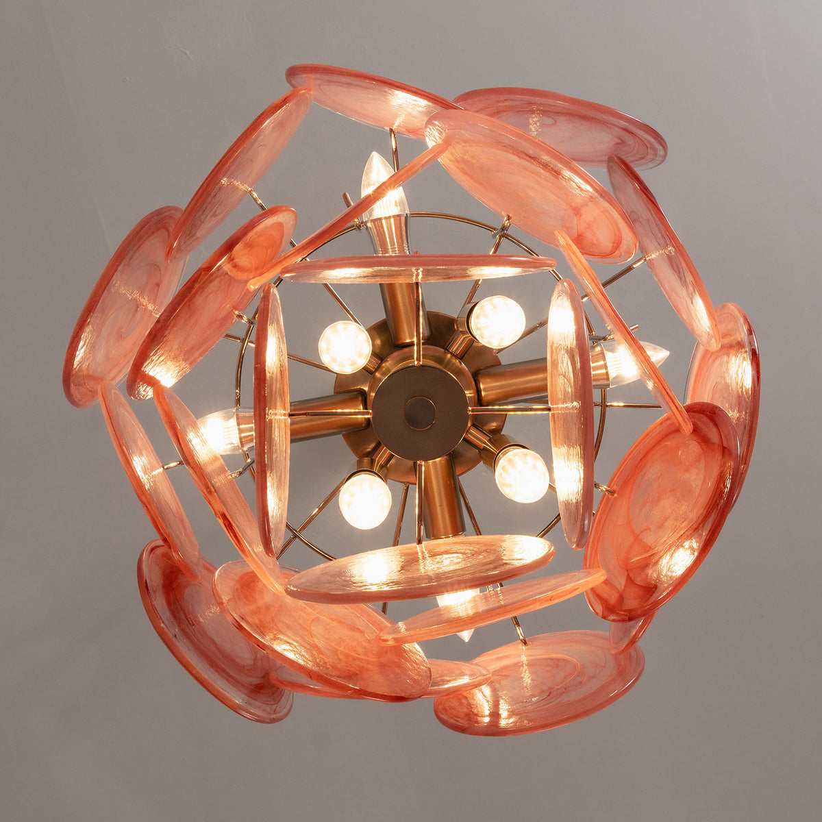 Vaucelle Swirled Glass Disc Tiered Chandelier | Swirled Glass and Brass | Bottom-up perspective view of glowing pink swirled glass disc chandelier | Severn Lighting