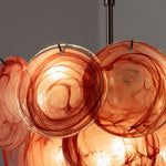 Vaucelle Swirled Glass Disc Tiered Chandelier | Swirled Glass and Brass | Close-up view of glowing reddish-orange swirled glass discs | Severn Lighting