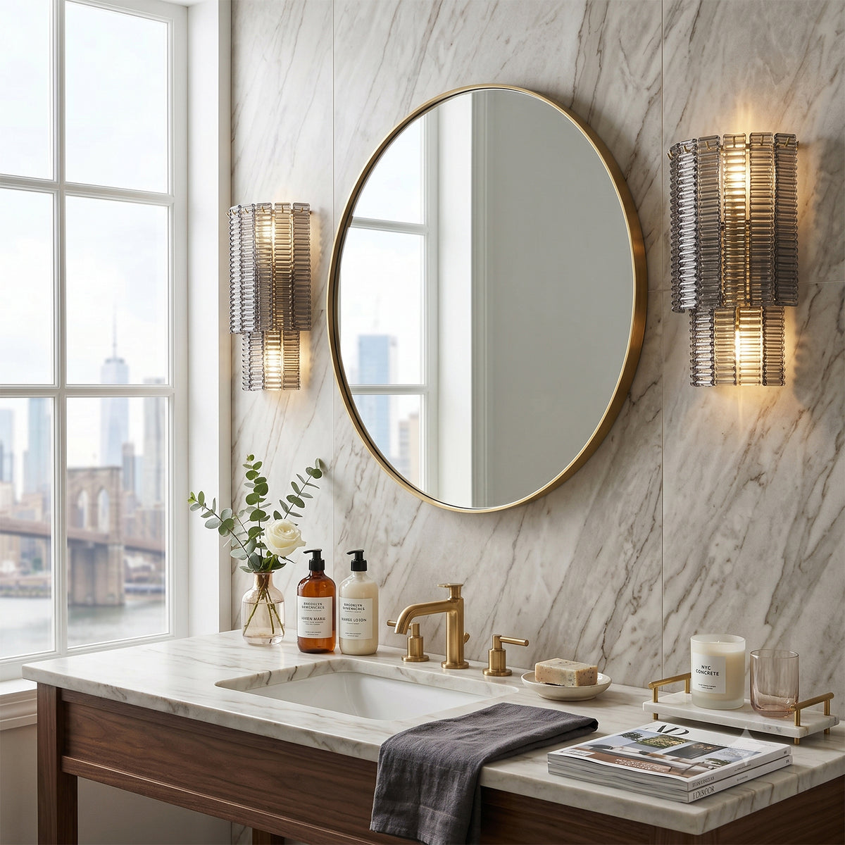 Vespera Tiered Smoky Glass Wall Lamp | Glass, Metal | A pair of smoky glass sconces symmetrically flanking a round gold mirror over a luxury marble bathroom vanity countertop | Severn Lighting