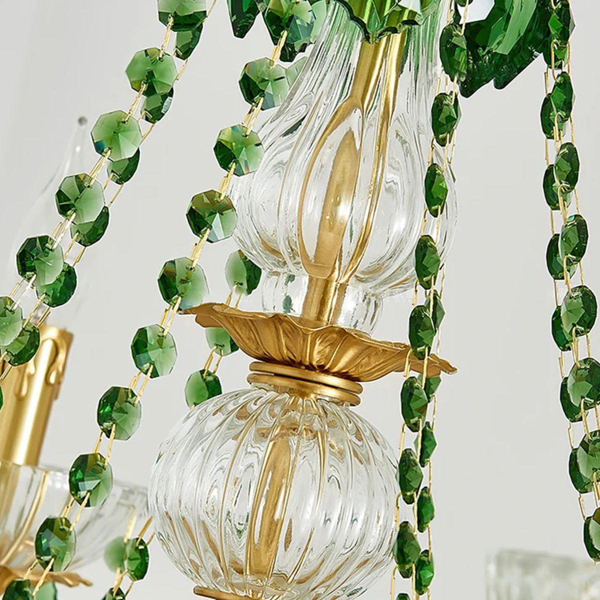 Vionne Green Crystal Drop Brass Chandelier | Green Crystal, Clear Glass and Brass | Close-up view focusing on the draped green crystal bead chains and central column | Severn Lighting