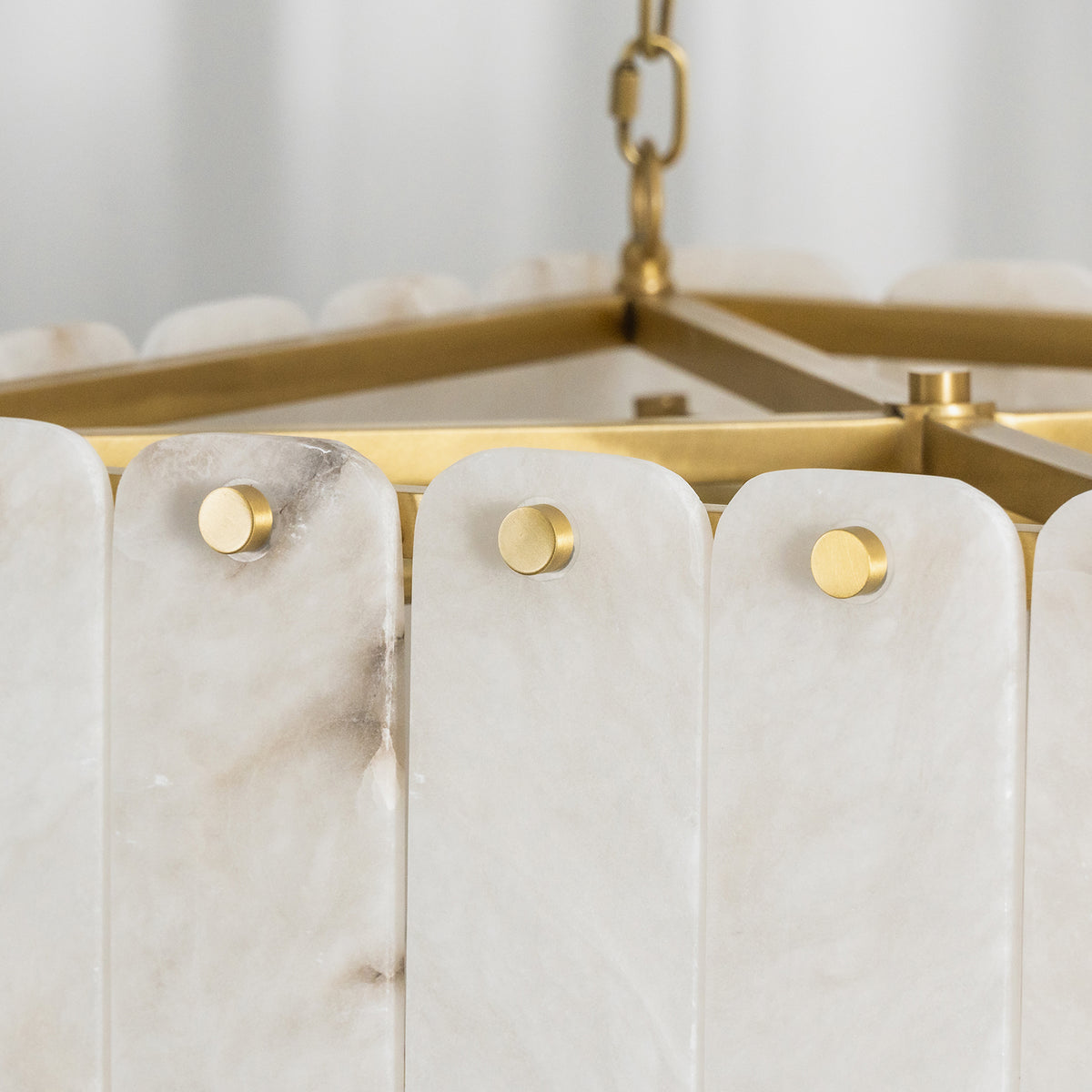 Vivienne Tiered Alabaster Chandelier | Alabaster, Brass | Close-up focus on the gold brass frame pins securing the vertical translucent white alabaster stone plates | Detail shot | Severn Lighting
