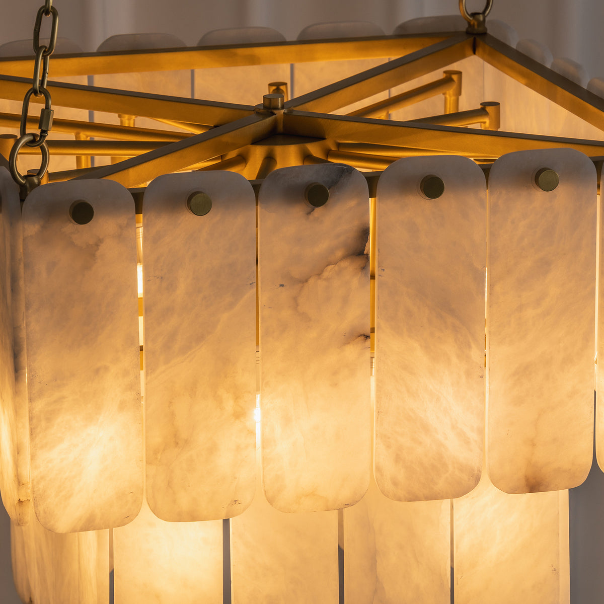 Vivienne Tiered Alabaster Chandelier | Alabaster, Brass | Close-up illuminated view showcasing the warm glow and organic mineral veining patterns of the layered stone tiles | Detail shot | Severn Lighting