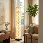 Alden Interlocking Alabaster Column Floor Lamp | Natural Alabaster and Metal | Positioned in a living room corner near a large window and plant | Severn Lighting