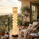 Alden Interlocking Alabaster Column Floor Lamp | Natural Alabaster and Metal | Styled on a terrace balcony with ocean view and lounge chair | Severn Lighting