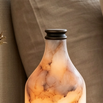 Aldric Alabaster Flask Table Lamp | Natural Alabaster Stone and Bronze Metal | Close-up macro view focusing on the narrow neck and bronze metal collar of the illuminated lamp | Severn Lighting