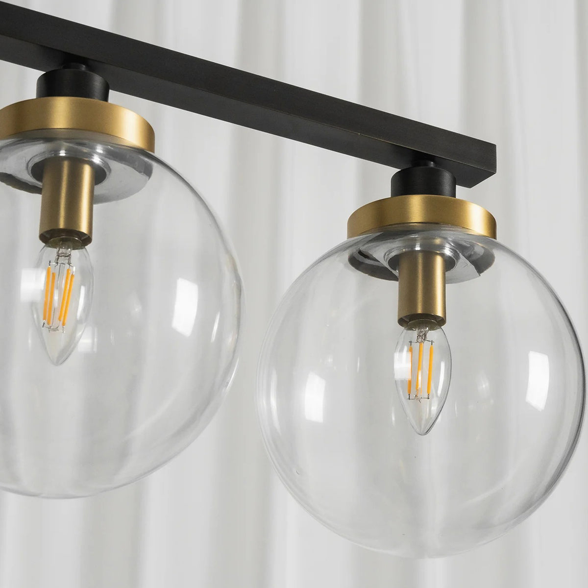 Alistair Linear Glass Globe Chandelier | Clear Glass Detail | Close-up unlit view of the clear glass globe shades highlighting the premium gold brass sockets and internal filament bulbs | Detail shot | Severn Lighting
