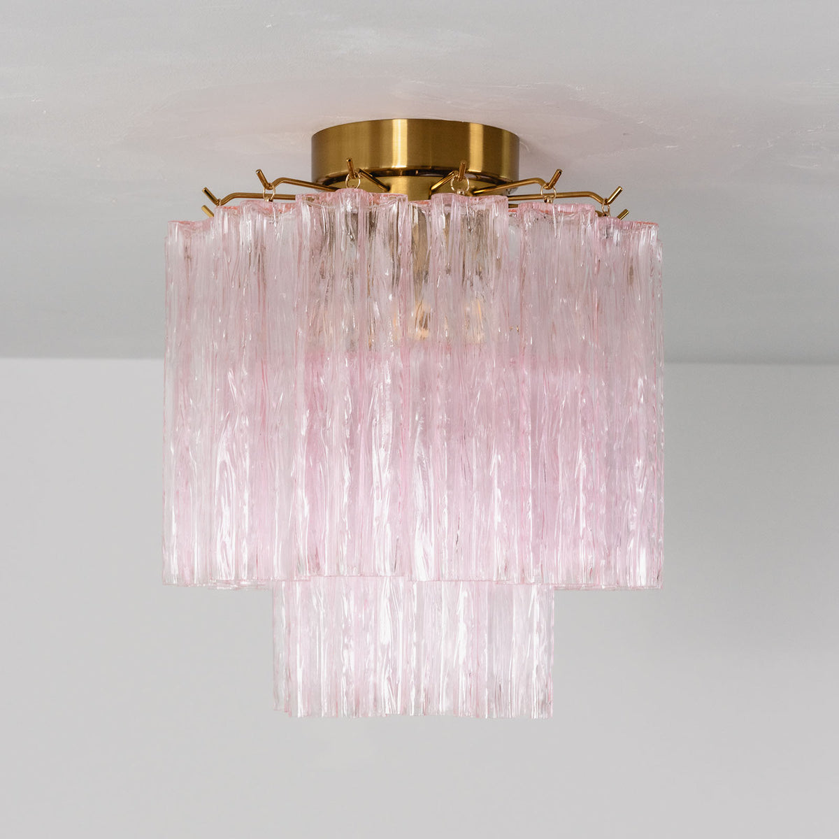 Amabel Dazzling Pink Glass Ceiling Light | Pink Glass and Brass | Full product view illuminated gracefully against a neutral grey wall | Severn Lighting