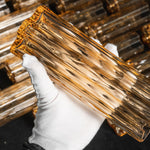 Ambleve Amber Glass Tube Flush Mount Chandelier | Fluted Amber Glass and Brass | Gloved hand holding a single fluted amber glass tube prism | Severn Lighting