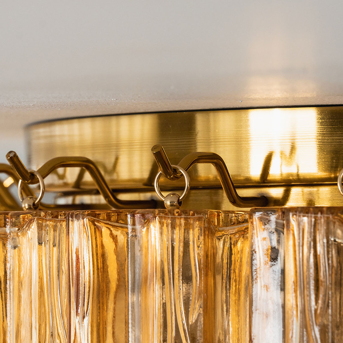 Ambleve Amber Glass Tube Flush Mount Chandelier | Fluted Amber Glass and Brass | Detail shot of top brass rim holding tiered amber glass tubes | Severn Lighting