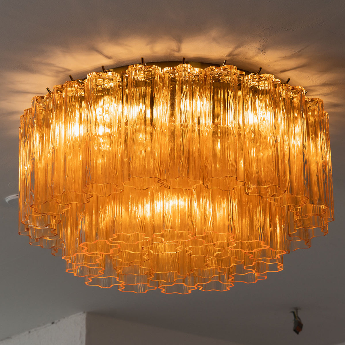 Ambleve Amber Glass Tube Flush Mount Chandelier | Fluted Amber Glass and Brass | Angled side view of the illuminated flush mount fixture on ceiling | Severn Lighting