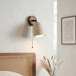 Aria Travertine Wood Wall Lamp | Travertine, Wood, Metal | Mounted on a white textured plaster wall above a woven cane headboard bed under soft natural light | Samu Lamp