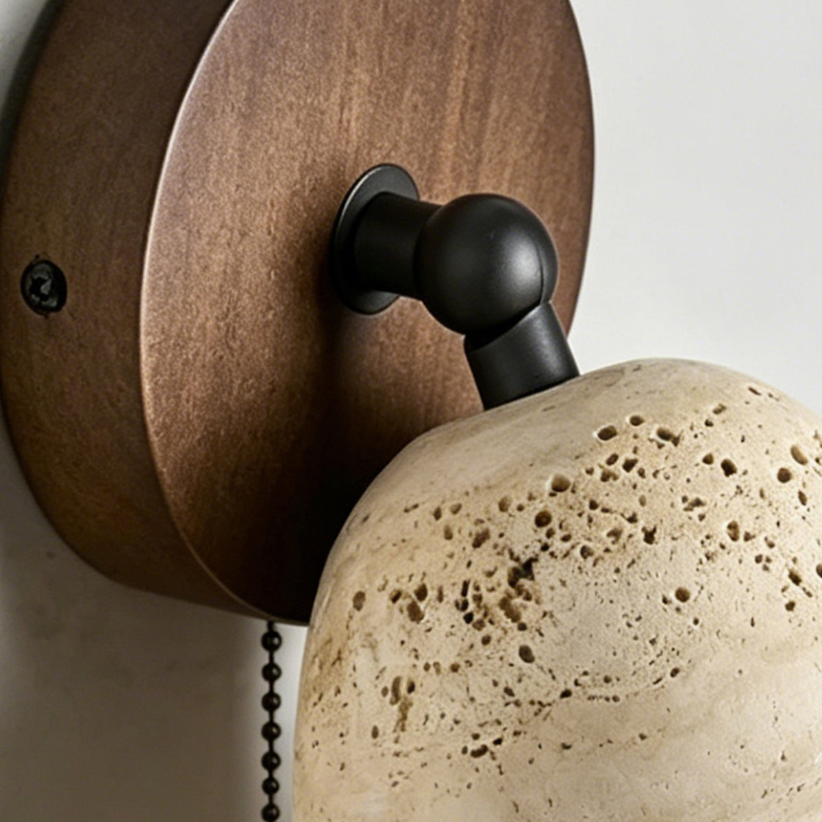 Aria Travertine Wood Wall Lamp | Travertine, Wood, Metal | Close-up view of the smooth circular walnut wood backplate and the black metal directional swivel joint | Detail shot | Samu Lamp