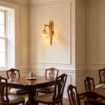 Armelle Rose Glass Brass Wall Lamp | Glass, Ceramic and Brass | Installed on a paneled dining room wall above a table with chairs | Severn Lighting