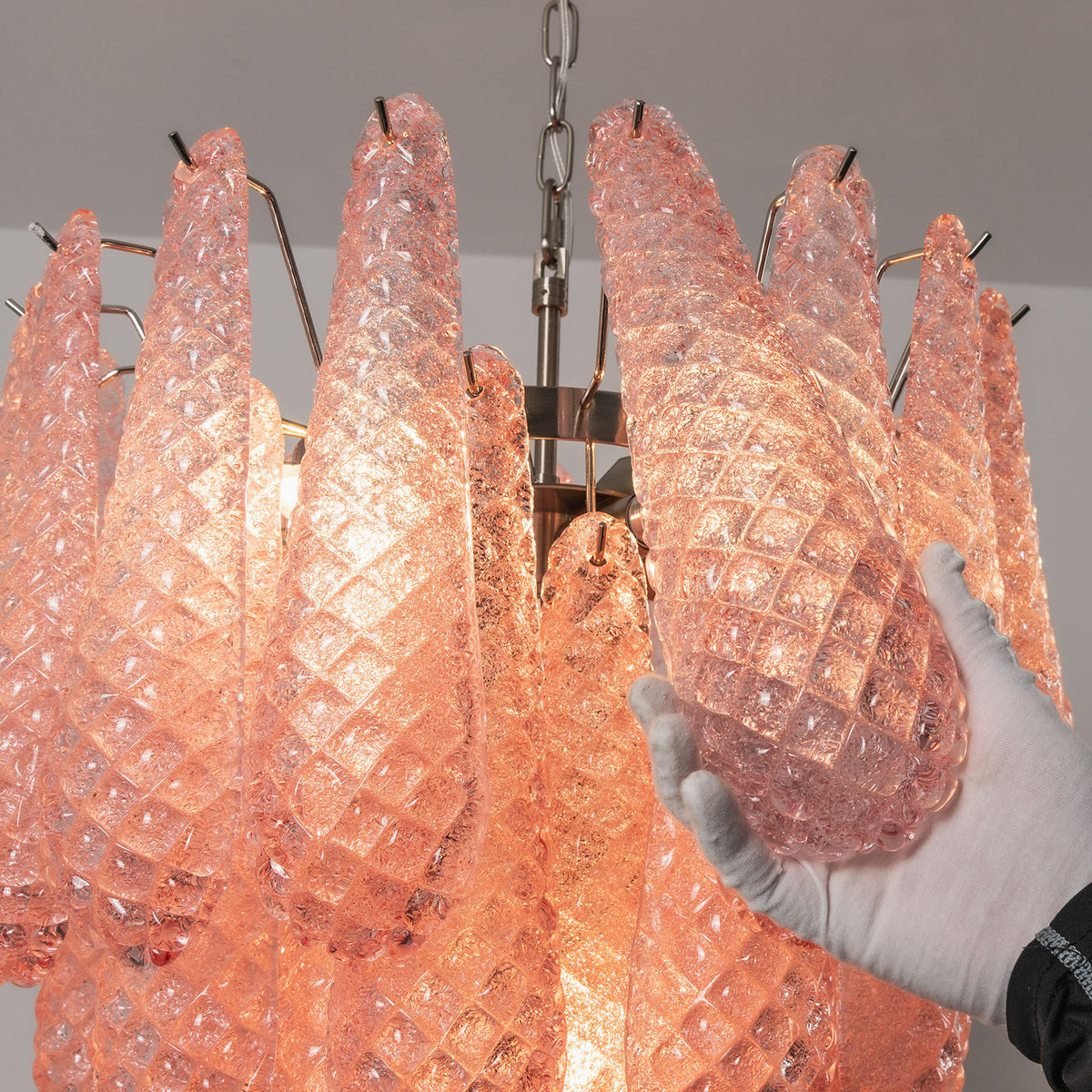 Aubine Pink Textured Glass Tiered Chandelier | Pink Textured Glass and Brass | Close-up side view of illuminated pink textured glass prisms on brass frame | Severn Lighting