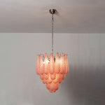 Aubine Pink Textured Glass Tiered Chandelier | Pink Textured Glass and Brass | Full view glowing softly displayed on a neutral studio wall | Severn Lighting