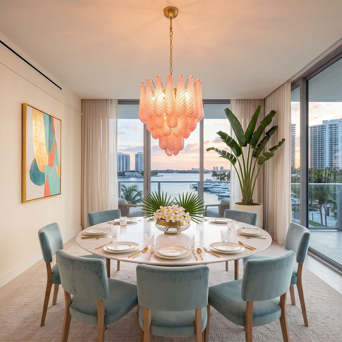 Aubine Pink Textured Glass Tiered Chandelier | Pink Textured Glass and Brass | Hanging above a round marble dining table with blue chairs and ocean views | Severn Lighting