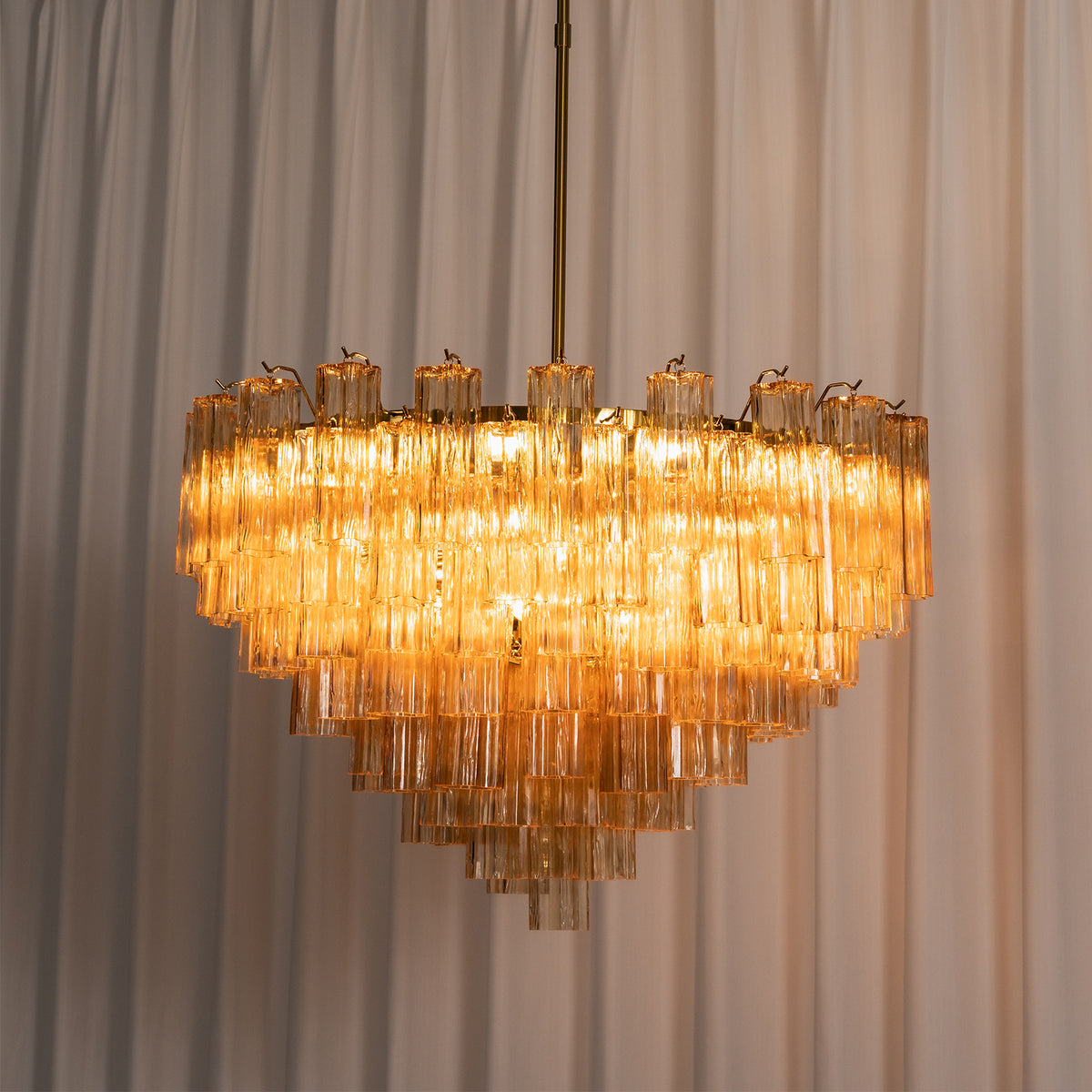 Auriane Fluted Amber Glass Chandelier | Fluted Amber Glass and Brass | Illuminated ambiance shot showing tiered amber glass warmth | Severn Lighting