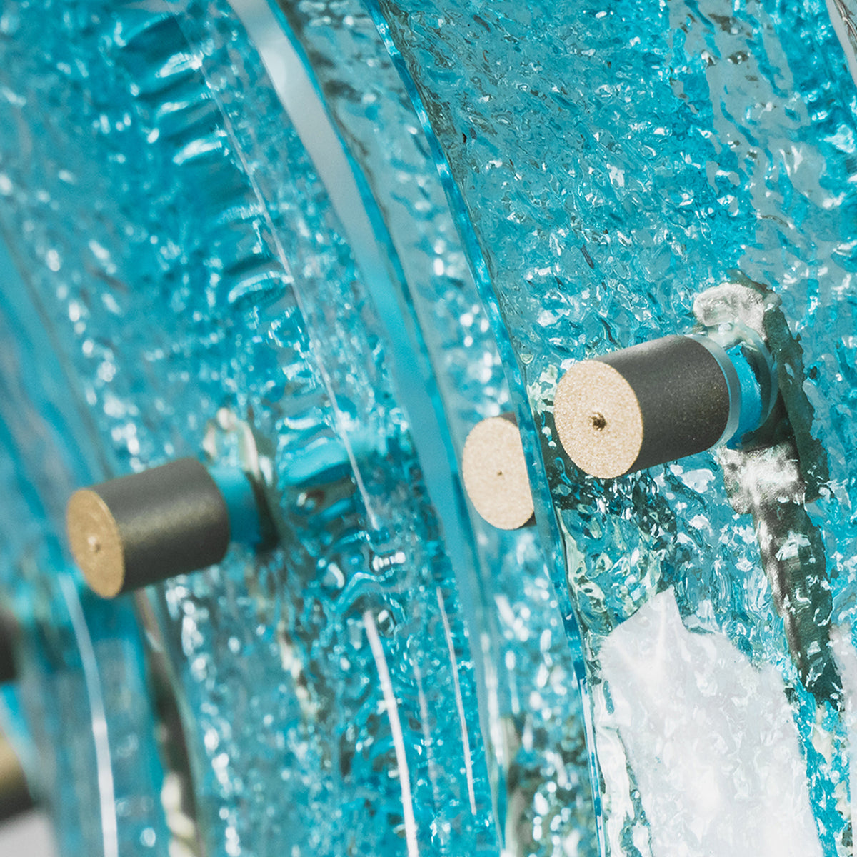 Azura Aquamarine Cascading Glass Chandelier | Glass, Metal | Macro close-up focus on the thick textured translucent aquamarine glass slats secured tightly by brass bolt hardware screws | Detail shot | Severn Lighting