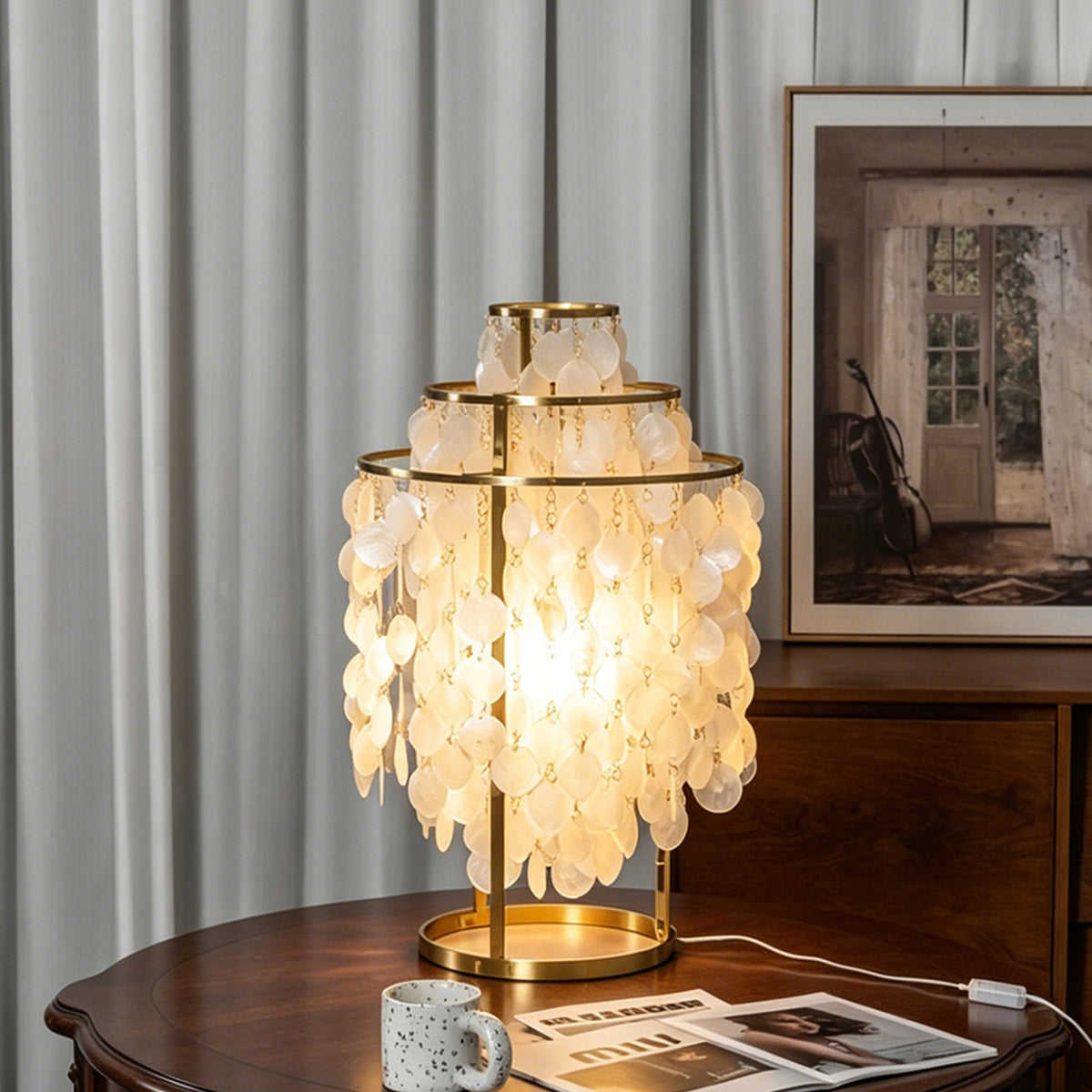 Callista Tiered Capiz Table Lamp | Capiz, Metal | Standing illuminated on a round dark wood table near vertical pleated window blinds in a refined traditional lounge room | Severn Lighting