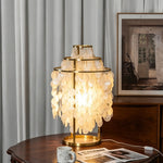 Callista Tiered Capiz Table Lamp | Capiz, Metal | Standing illuminated on a round dark wood table near vertical pleated window blinds in a refined traditional lounge room | Severn Lighting