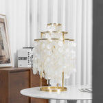 Callista Tiered Capiz Table Lamp | Capiz, Metal | Unlit view of the tiered natural seashell table lamp sitting on a minimalist white table in a contemporary residence space | Severn Lighting