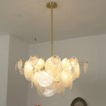 Celestia Art Glass Disc Chandelier | Glass, Metal | Studio view of the fully illuminated glass disc fixture casting a warm golden glow against a plain white wall | Severn Lighting