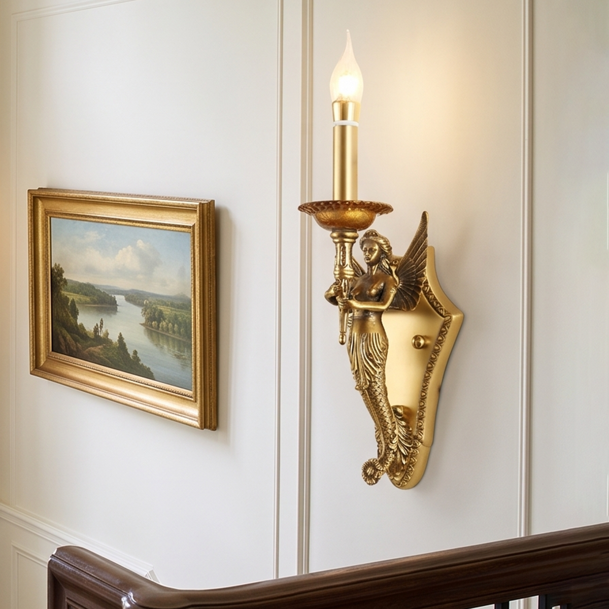 Clemency Winged Figure Brass Sconce | Cast Brass and Glass | Medium shot glowing beside a framed landscape painting near stairs | Severn Lighting