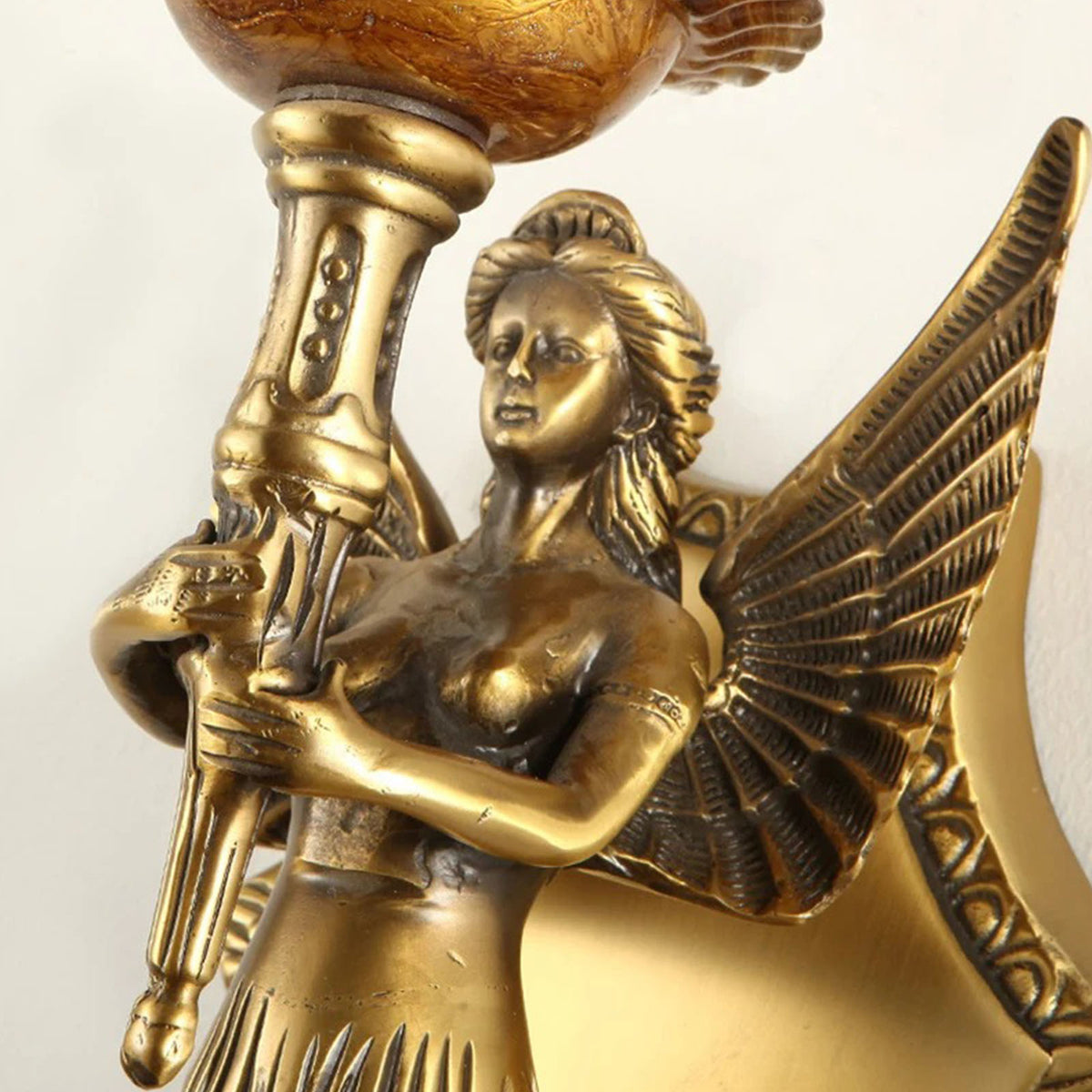 Clemency Winged Figure Brass Sconce | Cast Brass and Glass | Close-up highlighting the sculpted winged figure holding the torch stem | Severn Lighting