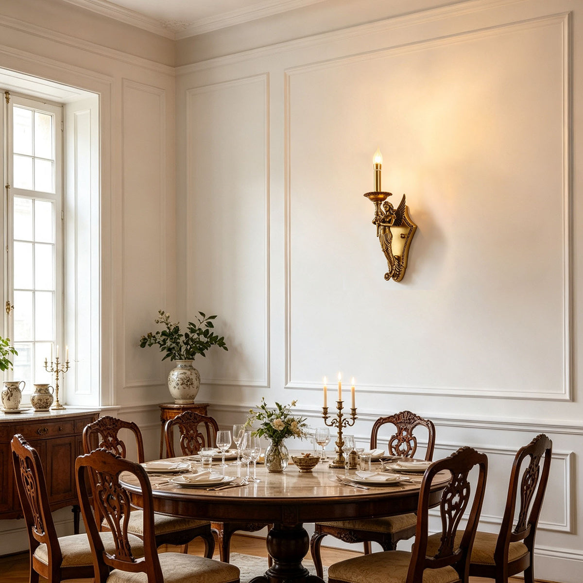 Clemency Winged Figure Brass Sconce | Cast Brass and Glass | Illuminating a classic dining room with a round wooden table | Severn Lighting