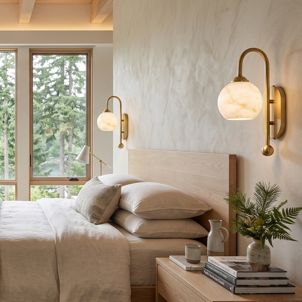 Cordelia Alabaster Globe Wall Sconce | Natural Alabaster and Brushed Brass | Styled on a light textured wall next to a wooden headboard and a potted green plant | Severn Lighting