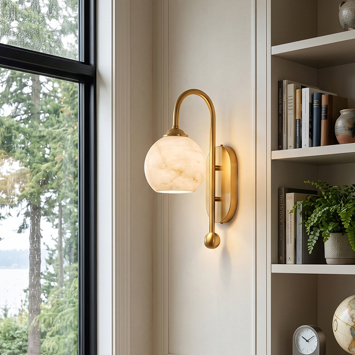 Cordelia Alabaster Globe Wall Sconce | Natural Alabaster and Brushed Brass | Styled on a slim white wall panel adjacent to a tall built-in library bookshelf | Severn Lighting